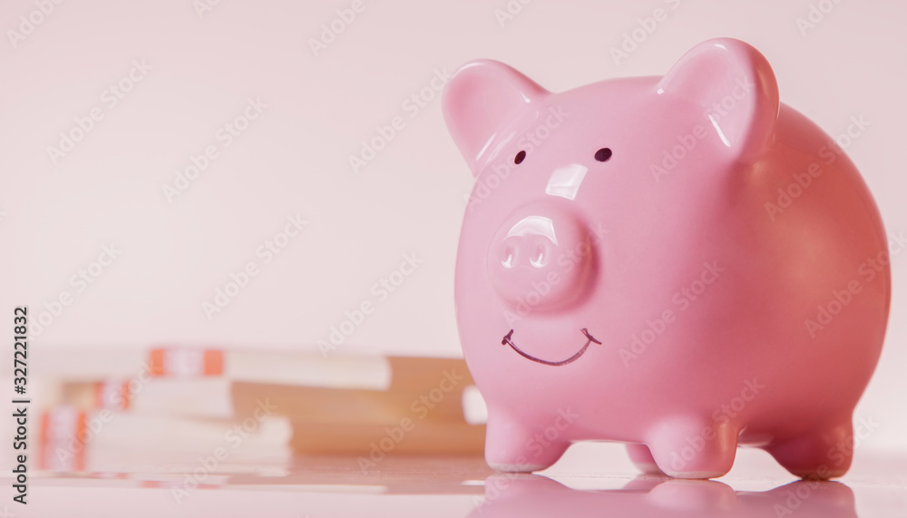 Pink piggy bank against money backgrouund as symbol of profit and success. Horizontal image. Pink piggy bank against money backgrouund as symbol of profit and success. Horizontal image.