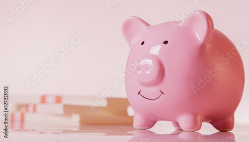 Pink piggy bank against money backgrouund as symbol of profit and success. Horizontal image. photo