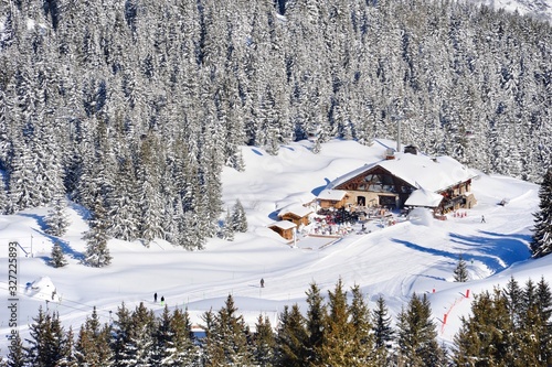 Areal view of Courchevel ski resort village in winter with forest and chalet in background 