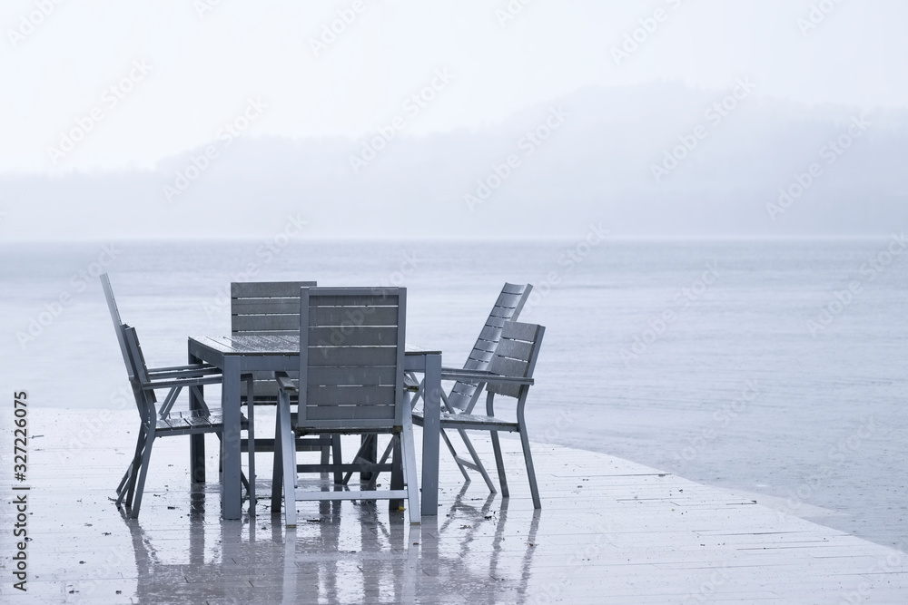 Wet British weather summer outdoor seat and table on decking in rain by lake at holiday home Loch Lomond Wet British weather summer outdoor seat and table on decking in rain by lake at holiday home Loch Lomond