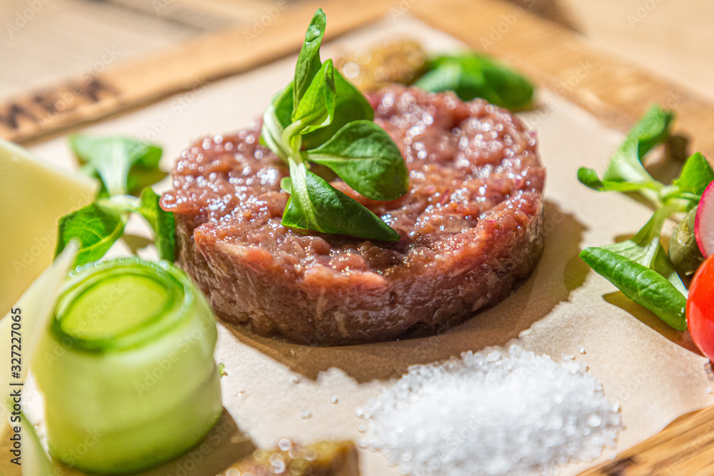 Tartare-a traditional appetizer of raw beef with spices lies on a wooden Board in the restaurant. Tartare-a traditional appetizer of raw beef with spices lies on a wooden Board in the restaurant.