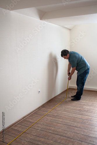 Man measuring white wall. Construction tool