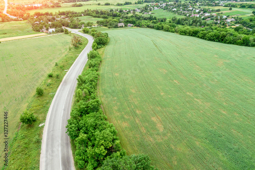 Summer rural landscape. Aerial view. View of the village, green fields, and road