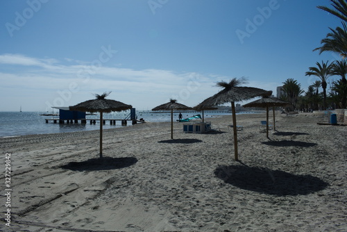 The beach at the beautiful resort of Lo Pagan, at the Mar Menor sea, in Spain. Sun beds and spring sunshine by the calm waters of the Mediterranean. 