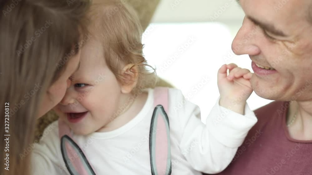 Close up face of laughing cheerful playful family having fun together. Carefree parents mother father and cute little baby smiling playing having positive emotion 4k footage Close up face of laughing cheerful playful family having fun together. Carefree parents mother father and cute little baby smiling playing having positive emotion 4k footage