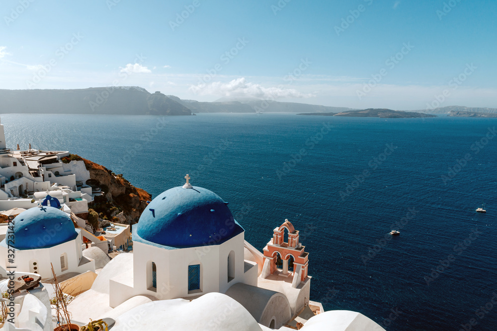 Blue domed church in Oia overlooks the spectacular caldera surrounding the beautiful island of Santorini, Greece