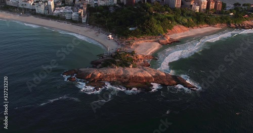Aerial panning view of Arpoador peninsula at sunrise. Famous sunset spot and surfing area in Rio de Janeiro, Brazil. Ocean waves crashing on the rocks