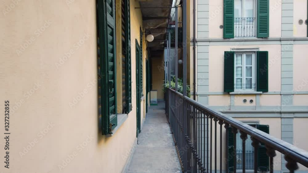A resident of the house walks along a narrow Italian balcony-terrace. The courtyard of a traditional Milan multi-story apartment building. First perspective. A resident of the house walks along a narrow Italian balcony-terrace. The courtyard of a traditional Milan multi-story apartment building. First perspective.