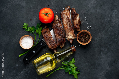 grilled pork ribs over meat knife with spices on a stone background
