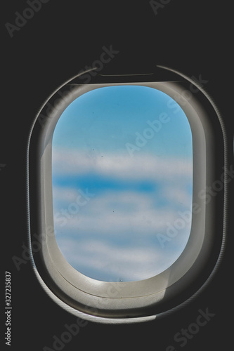 Ventana de un avión con nubes desenfocadas 