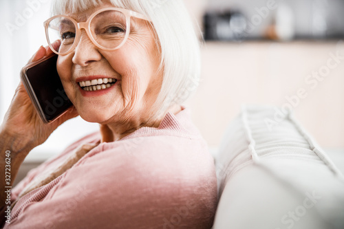 Cheerful old lady in glasses talking on cellphone
