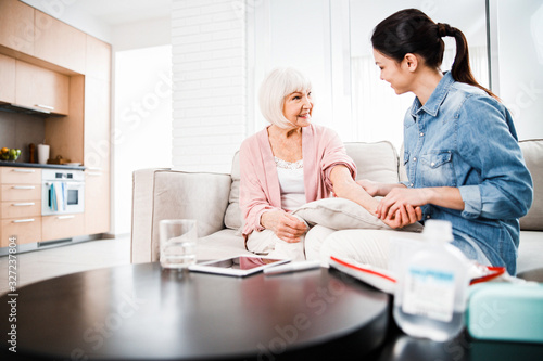 Family doctor checking arm of smiling old woman