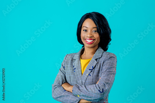 Portrait of a  happy smiling young woman in business jacket with arms crossed isolated on blue