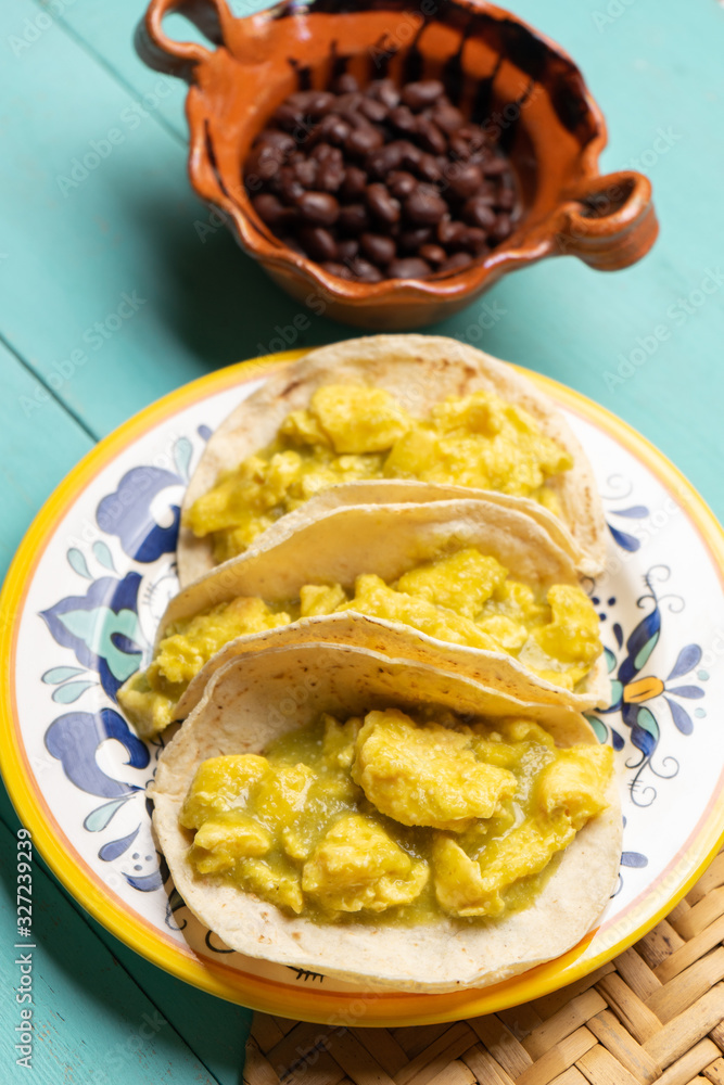 Mexican scrambled eggs tacos with green sauce on turquoise background