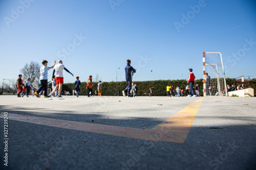 unrecognizable young boys and girls playing soccer in the schoolyard