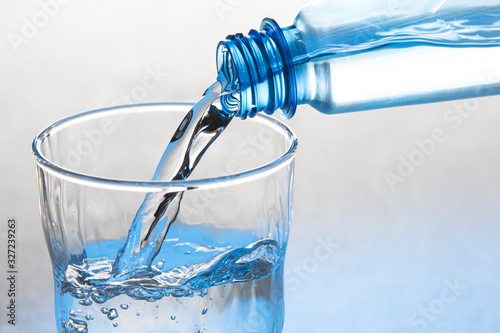 Water is pouring from a bottle into a glass Isolated on a white background