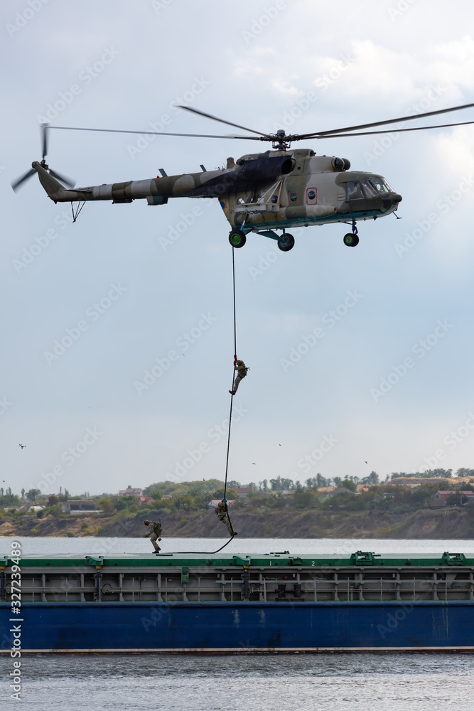 Soldiers descend from a helicopter to a barge Soldiers descend from a helicopter to a barge