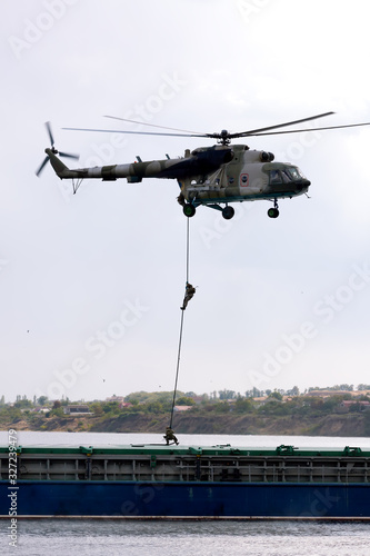 Soldiers descend from a helicopter to a barge
