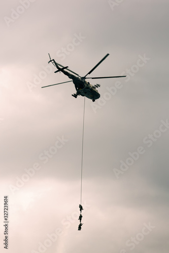 Soldiers go down a rope from military helicopter.