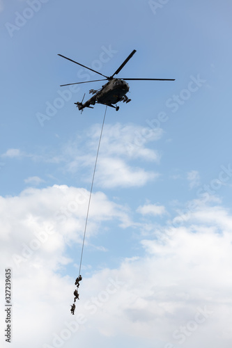 Soldiers go down a rope from military helicopter.
