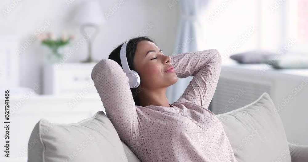 Serene african woman relaxing on sofa wear headphones listening music Serene african woman relaxing on sofa wear headphones listening music
