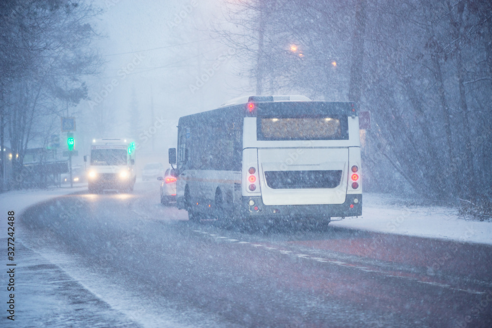 Buses move on the road at winter evening time.