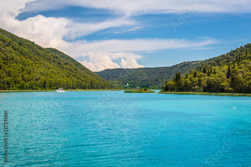 Green hills with forest around Krka river with touristic boats in beautiful Krka National Park, Croatia