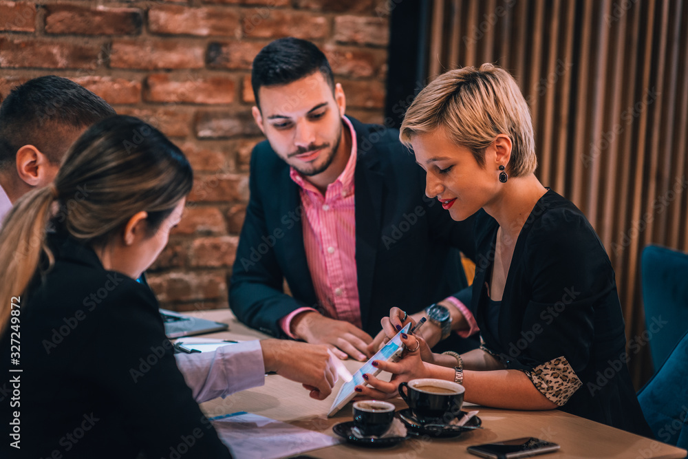 Diverse colleagues, sharing thoughts on the project and analyzing statistics and strategy while enjoying their coffee in a cafe. Diverse colleagues, sharing thoughts on the project and analyzing statistics and strategy while enjoying their coffee in a cafe.