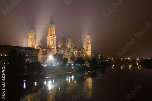 Cathedral of Our Lady of the Pillar illuminated on a foggy night