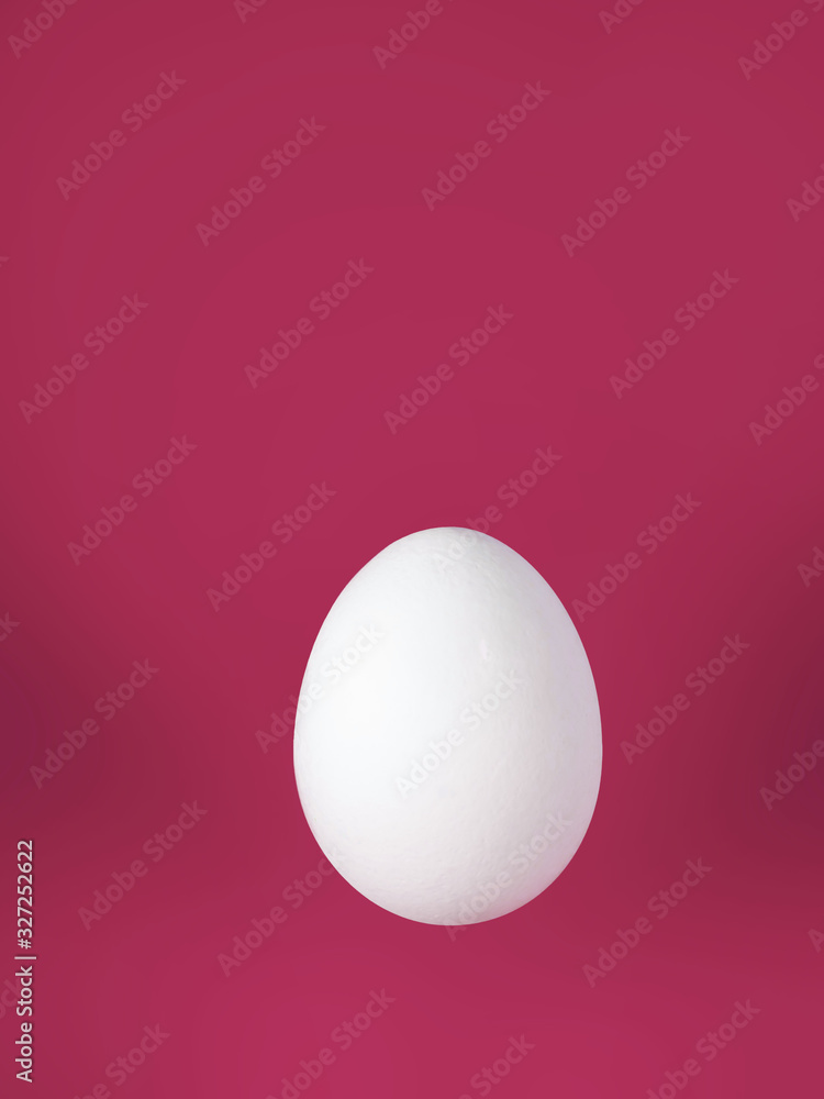vertical photo of a white egg in the corner of the frame on a red background