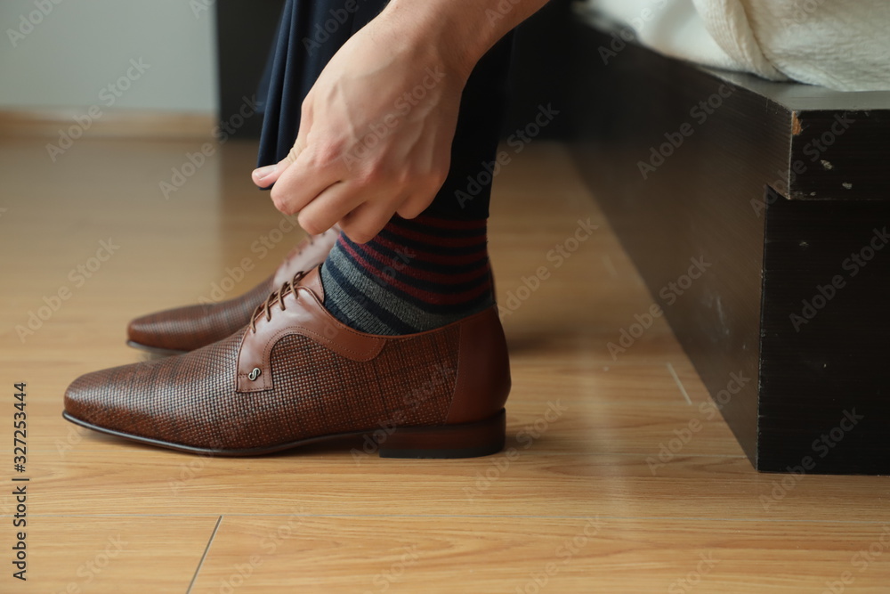 Pies de persona con zapatos, arreglando la parte de abajo, manos tocando pantalón de vestir Pies de persona con zapatos, arreglando la parte de abajo, manos tocando pantalón de vestir