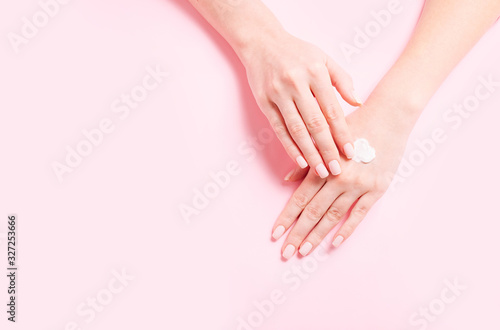 Woman's hands with natural cream. Care about soft, smooth skin. Beautiful fresh roses on pink table.