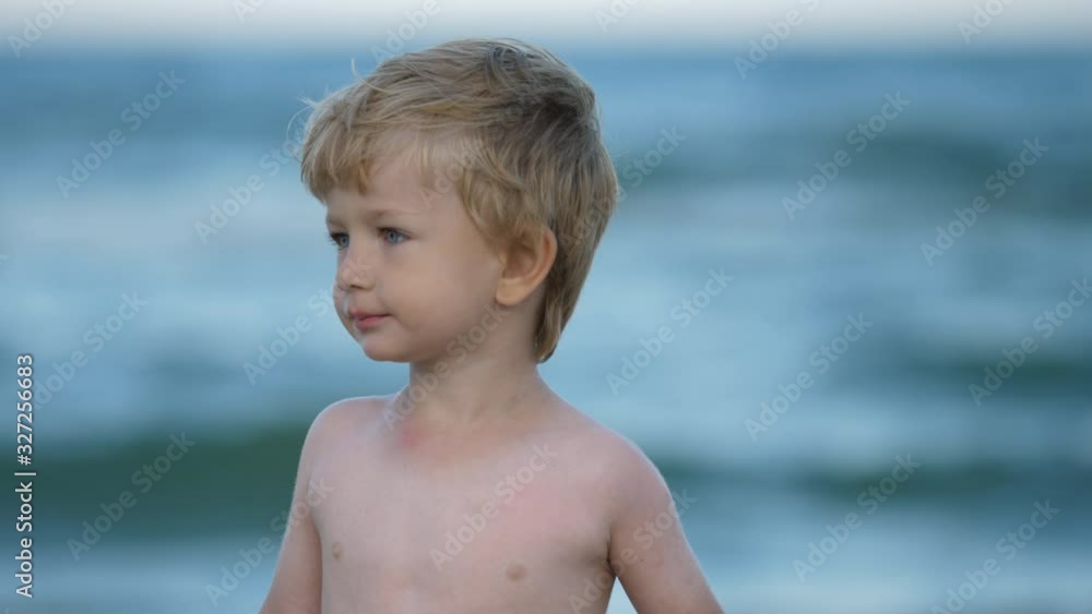 Portrait of little child with blue eyes, wind waves blond hair, funny boy at sea, fluttering, slow motion Portrait of little child with blue eyes, wind waves blond hair, funny boy at sea, fluttering, slow motion