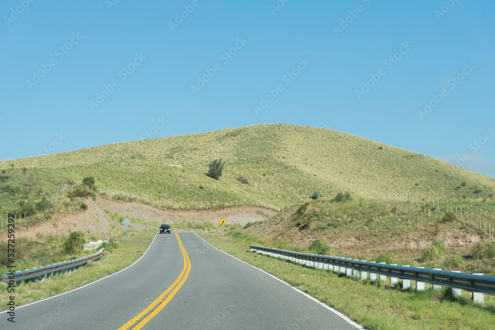 Mountains of Cordoba, Argentina: road, a car, grassy hill and cloudless sky