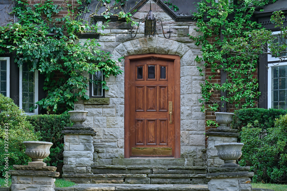 elegant wooden front door of stone house with flower pots and vines