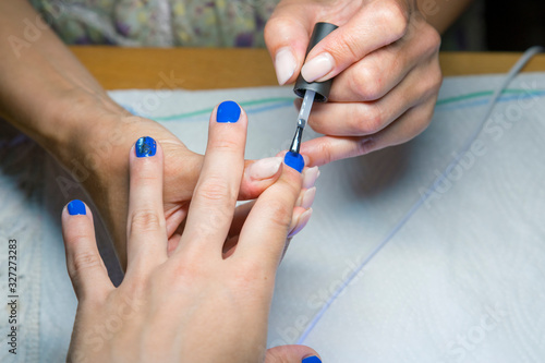 Beautiful manicure process. Nail polish being applied to hand  polish is a blue color. close up