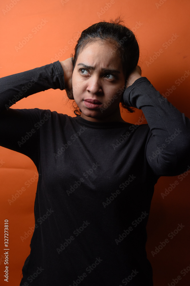 Confused middle eastern girl puts her hands on the head. Portrait of young sad girl closing her ears, hear nothing, deafness concept

