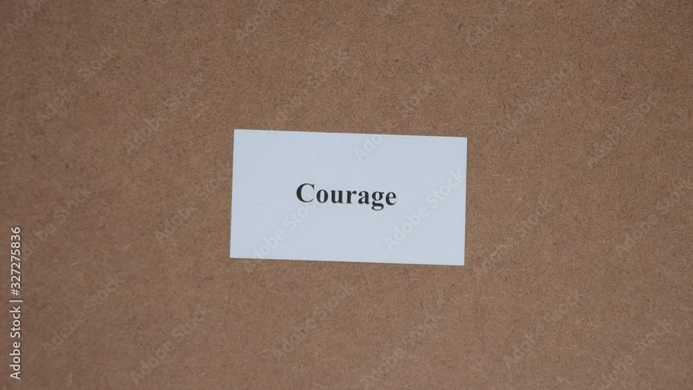 COURAGE. Top shot - Hand puts paper card with word. CORE VALUE concept. COURAGE. Top shot - Hand puts paper card with word. CORE VALUE concept.