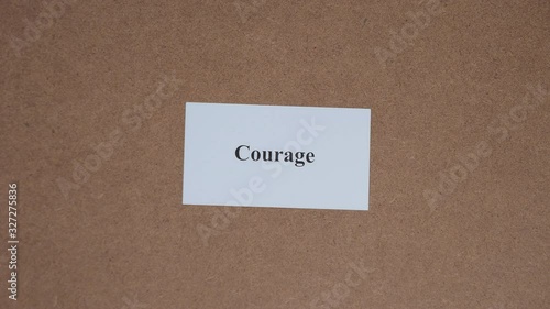COURAGE. Top shot - Hand puts paper card with word. CORE VALUE concept.