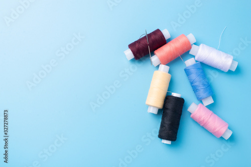 Colored spools of sewing thread on a blue background. Copy space. Top view