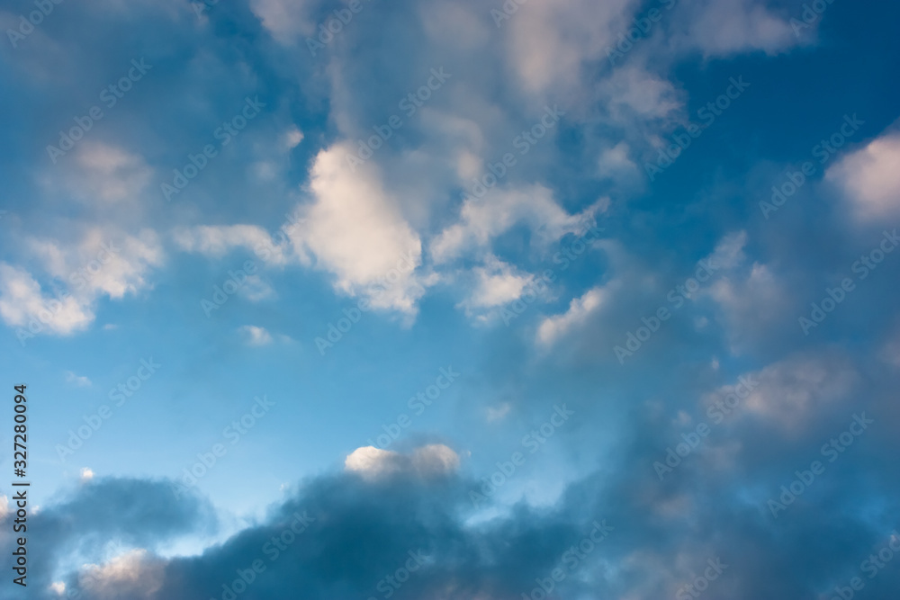 Blue sky with contrasting light and dark cumulus clouds. Sky pattern.