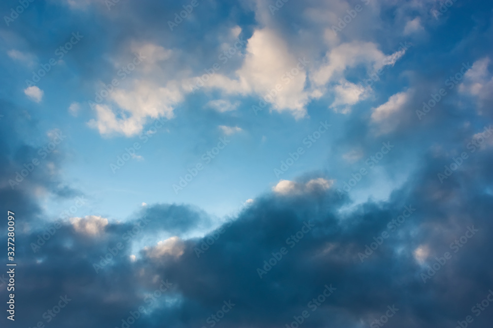 Blue sky with contrasting light and dark cumulus clouds. Sky pattern.