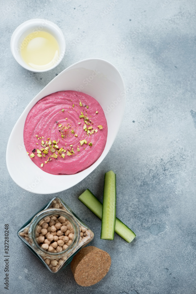 Hummus with addition of beetroot over light-blue stone background, flatlay with copy space, vertical shot Hummus with addition of beetroot over light-blue stone background, flatlay with copy space, vertical shot