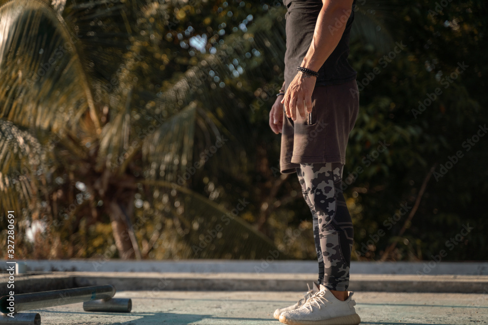muscular sports man in sneakers and sports uniform stands on the outdoor sports ground and prepares for exercises