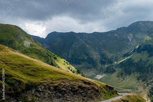 Car passing on a mountain road with mountain and dark clouds in the background