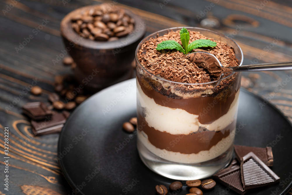 Classic tiramisu dessert in a glass cup on wooden background