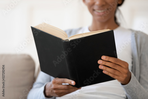 African American woman reading book relaxing at home