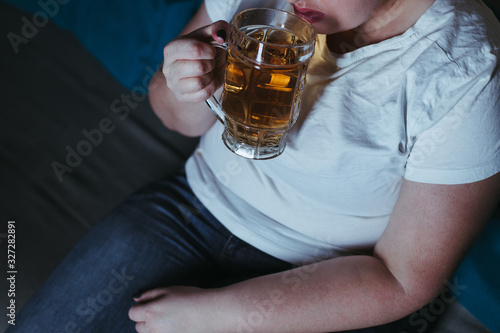 Lonely woman watching tv drinking beer late in the night. Alcohol addiction, depression, loneliness