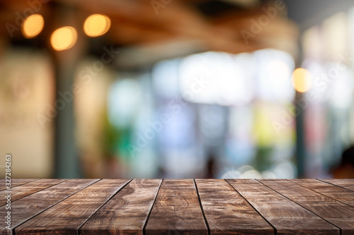 Empty wood table top and blur glass window interior restaurant banner mock up abstract background - can used for display or montage your products.