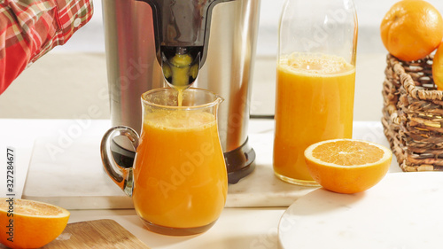 Fotografía Fresh orange juice in a glass jug close up on white background